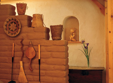 
Some interior walls are unfinished adobe brick, like this partial one, which makes a cozy nook to house the woodstove. Adobe acts as thermal mass, storing heat from the stove and releasing it after the fire burns out.

